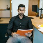 Serious businessman reviewing a document while sitting in a modern office.