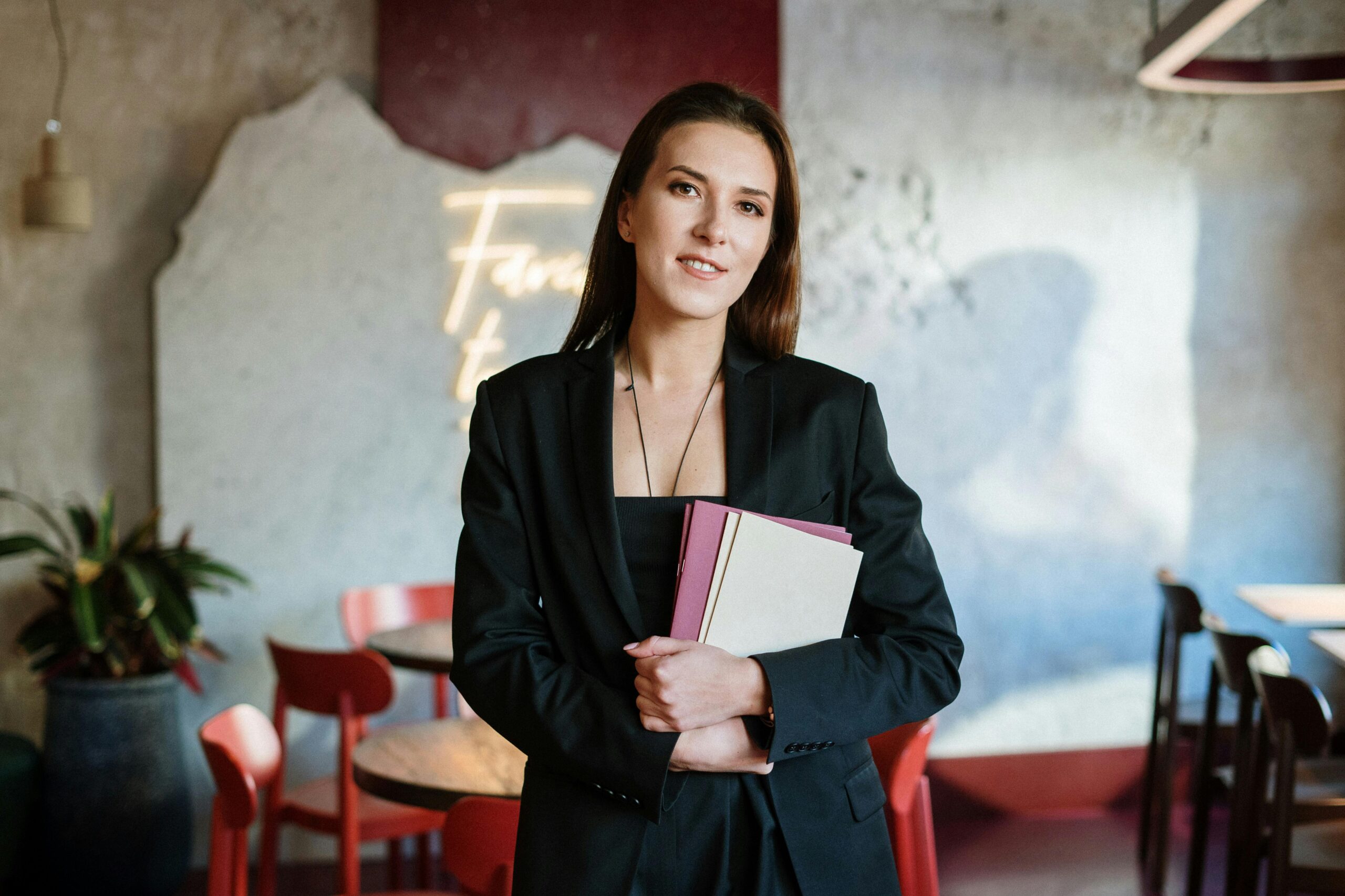 Home A young woman in a stylish café holding a menu, exuding confidence amidst a chic interior.